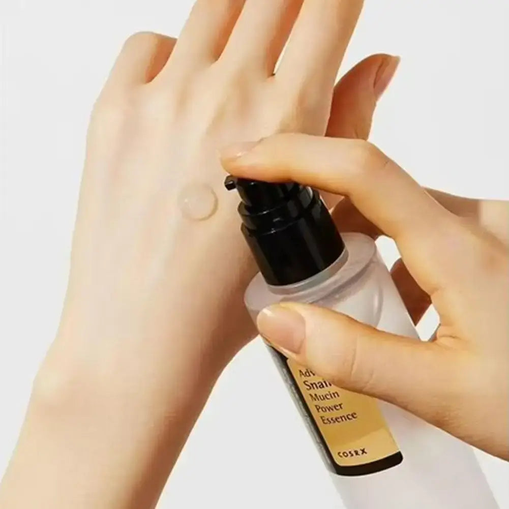 Applying Essence Advanced Snail 96 COSRX serum visage anti age on hand, showcasing its moisturizing properties.